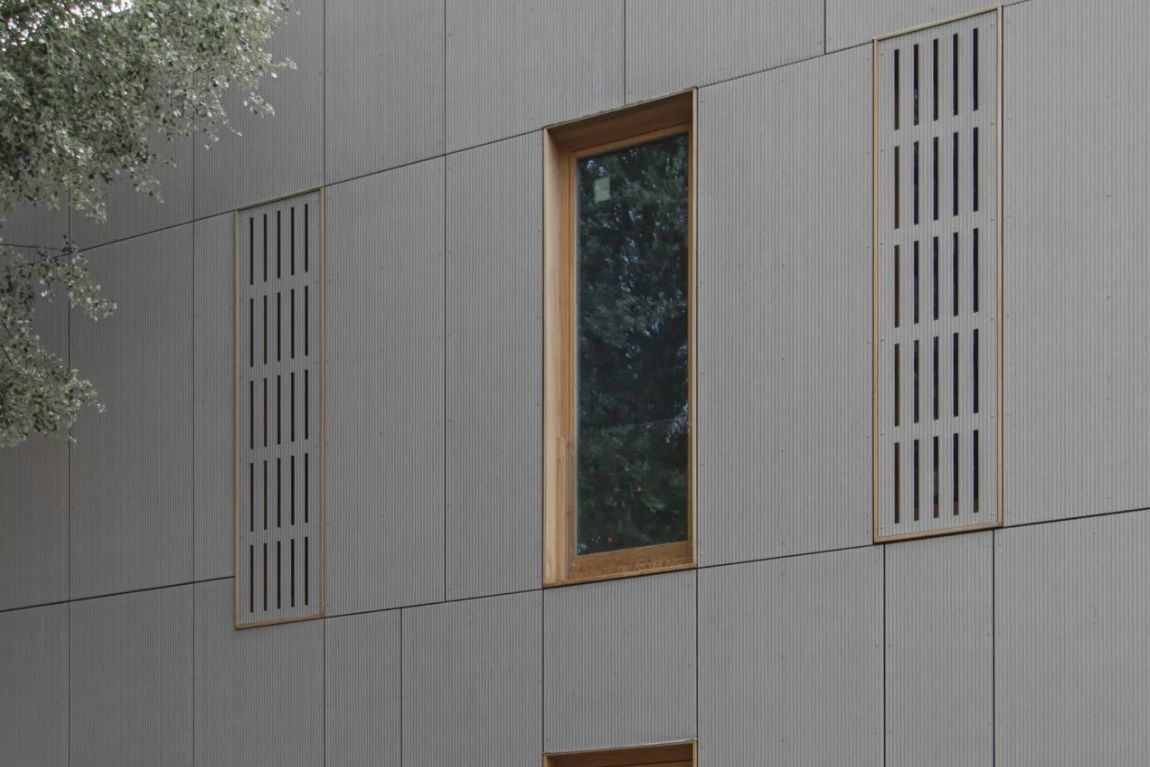 Close-up of grey fibre-cement rainscreen cladding panels with ventilated louvre detailing