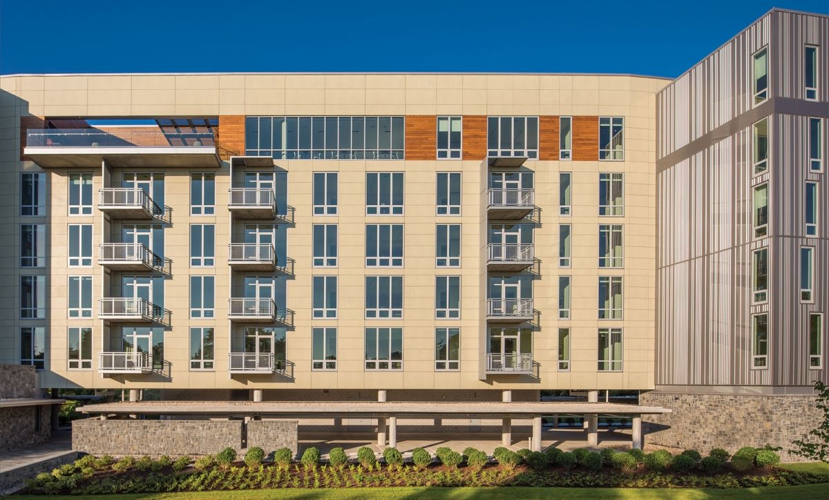 Modern multi-storey residential apartment building with balconies and mixed façade cladding
